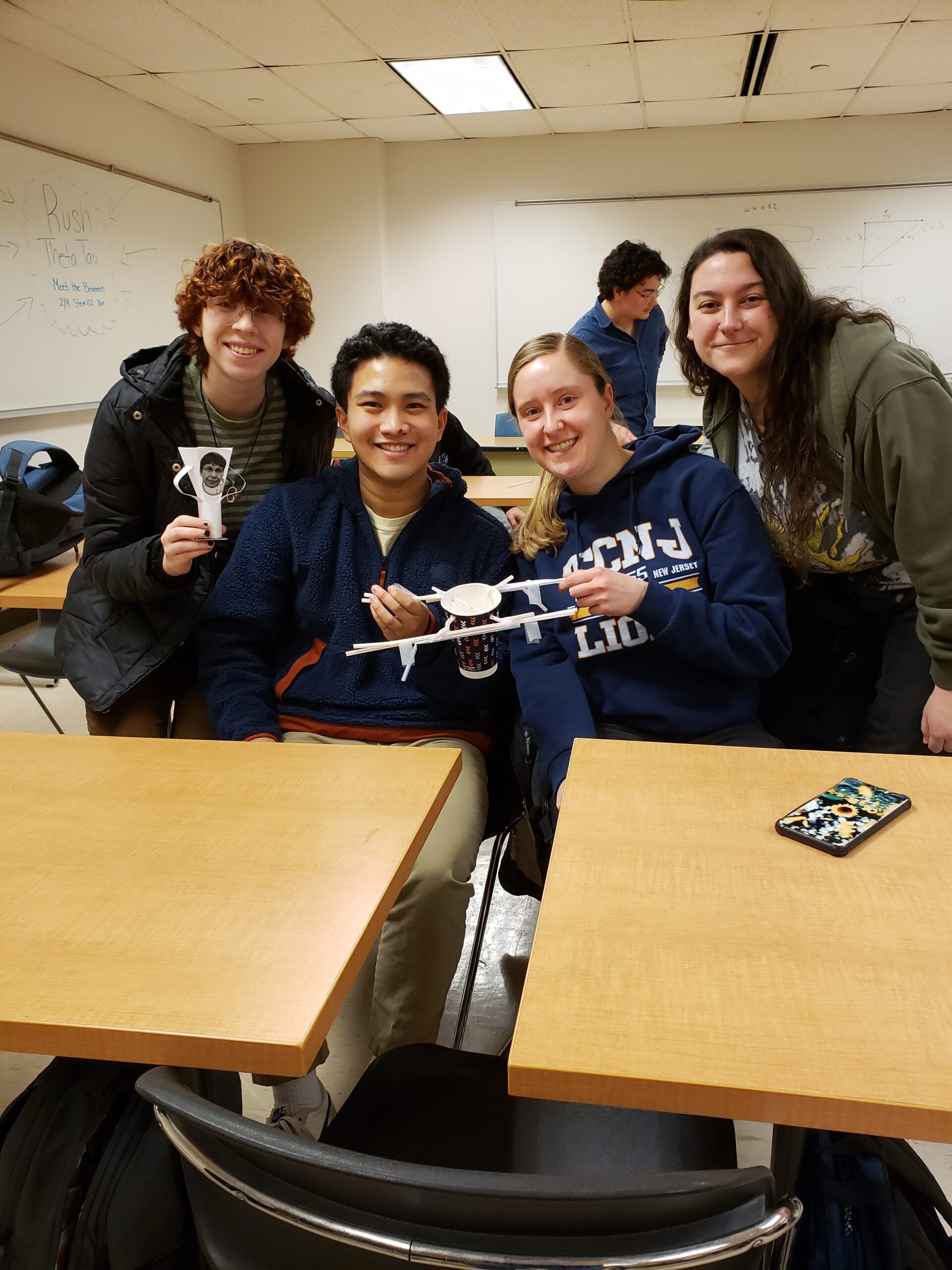 Seniors Dora Krstic, Josh Romero, Jill Stanton, and Mackenzie Bosland with the winning bridge design and the Krstic Cup standing behind a desk.