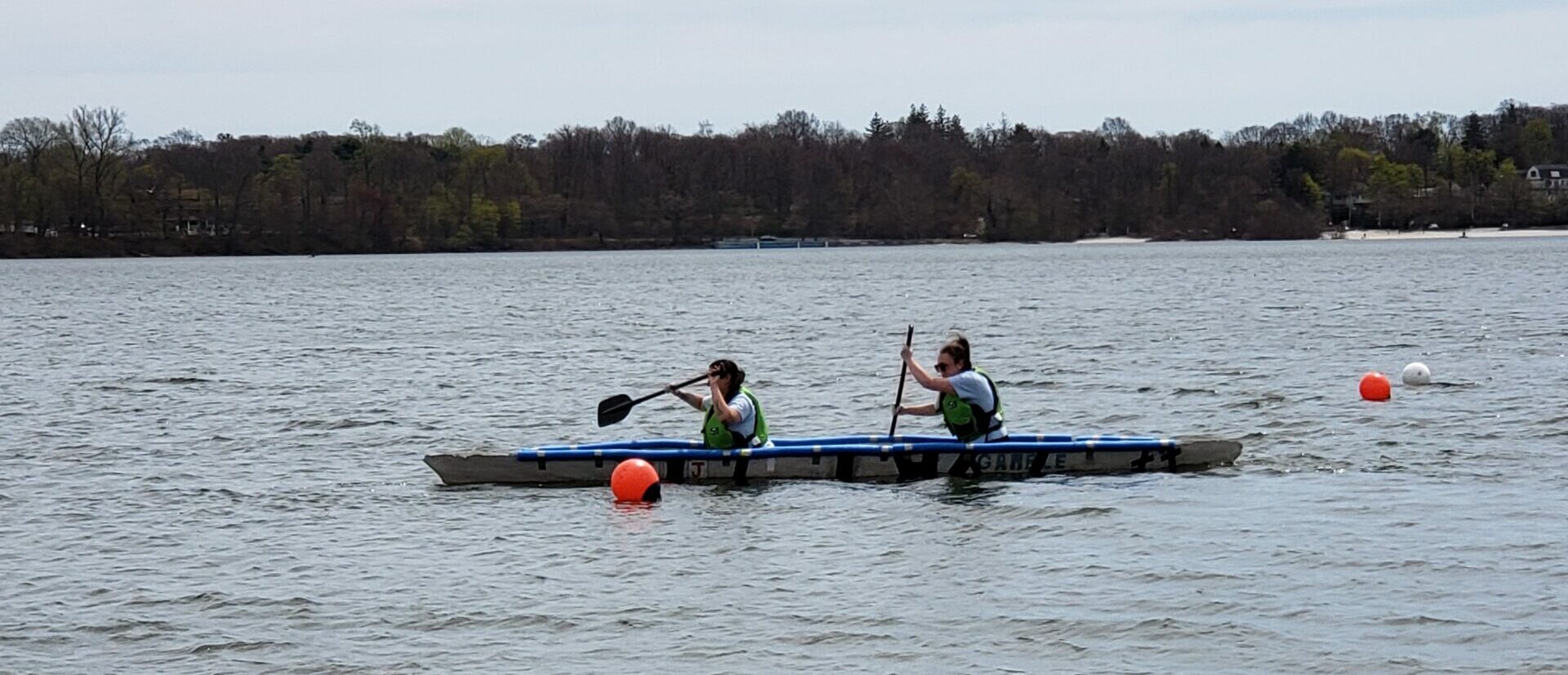 Two female students pedaling a canoe during a slalom race.