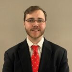 Andrwe Byrne headshot, male, brown hair, glasses, dark suit and red tie