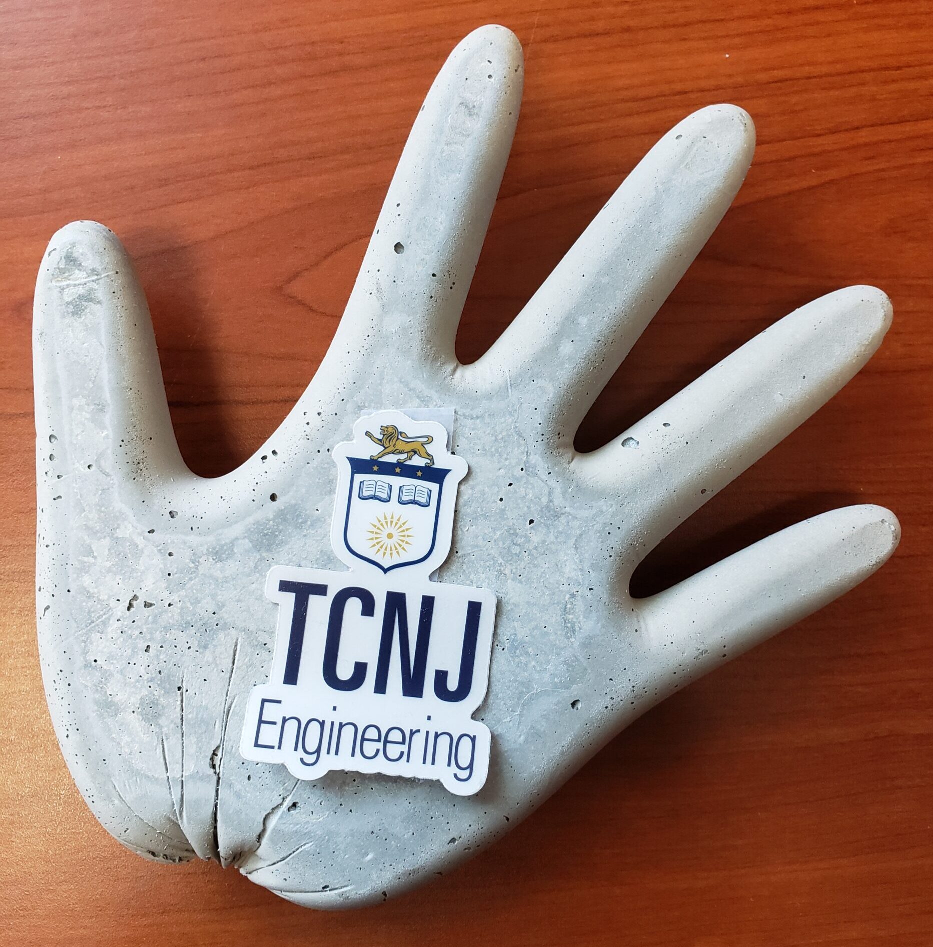 Hand made of concrete. TCNJ Engineering sticker is placed in the middle.