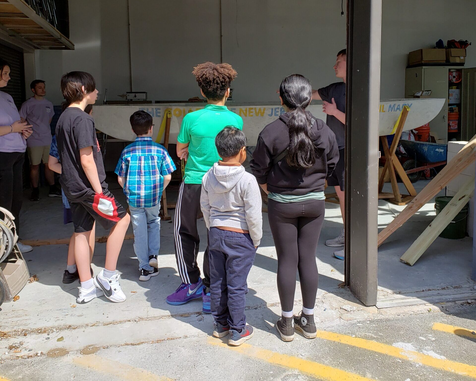 A group of children standing in front of a concrete canoe.