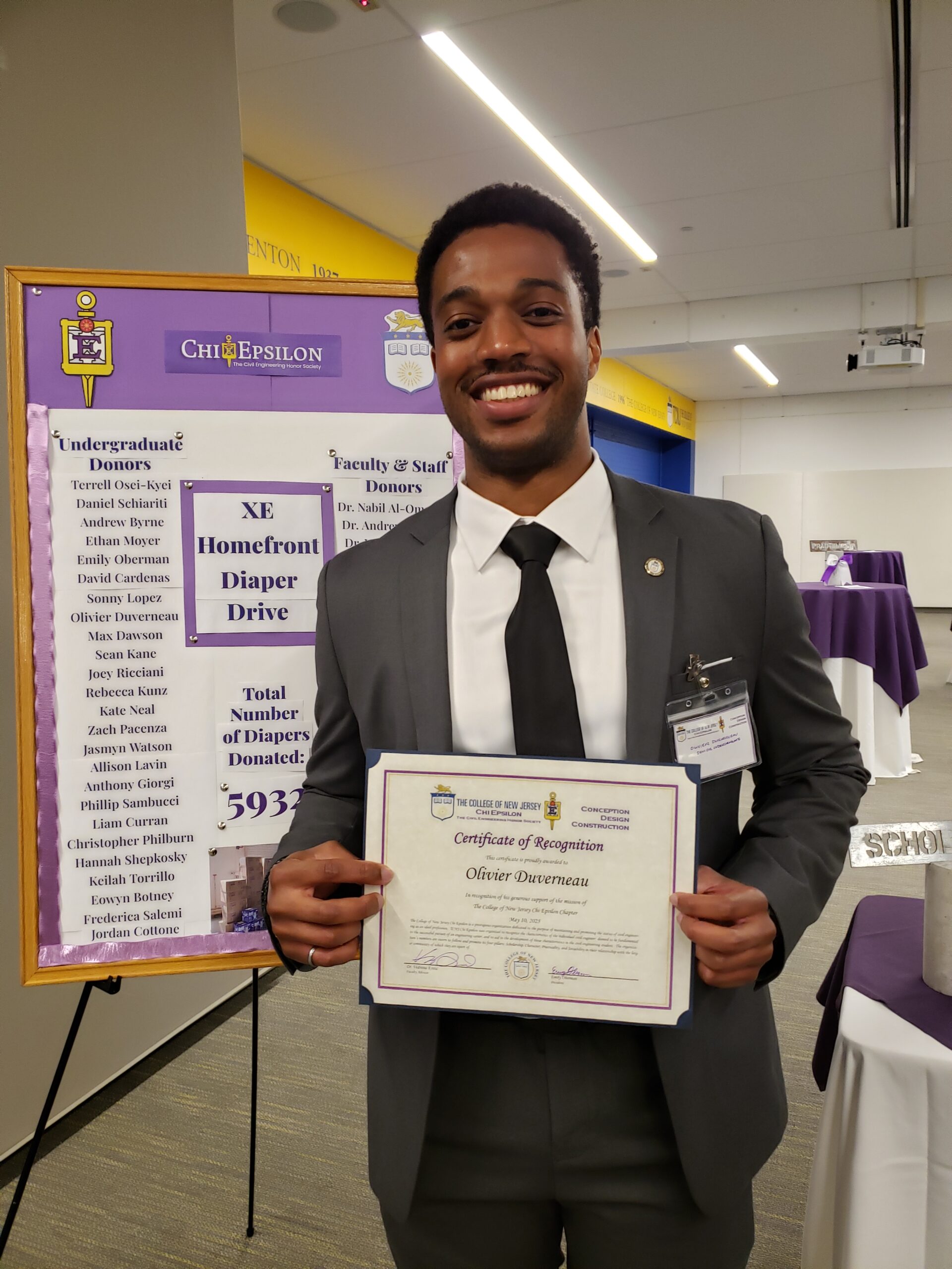 A student stands and holds an award certificate.