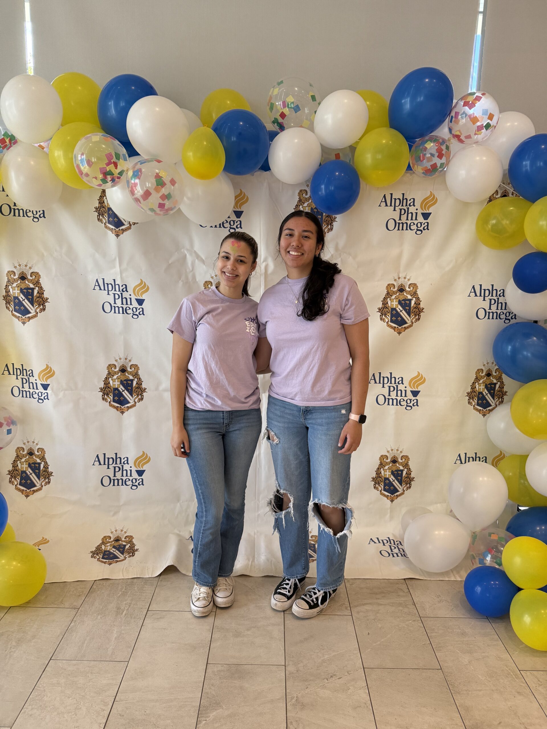 Two female students in purple shirts standing.