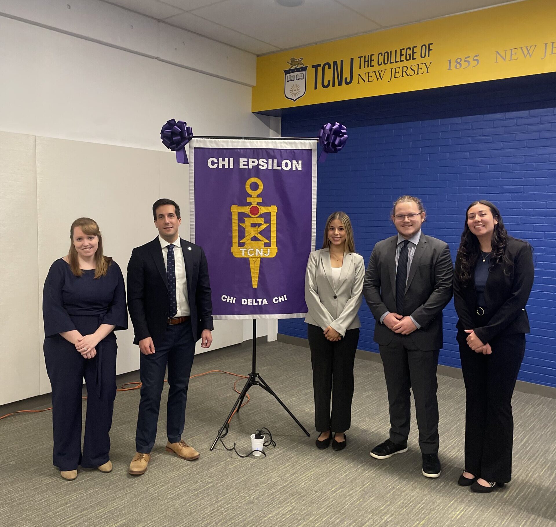 A group of people stands on each side of a banner.
