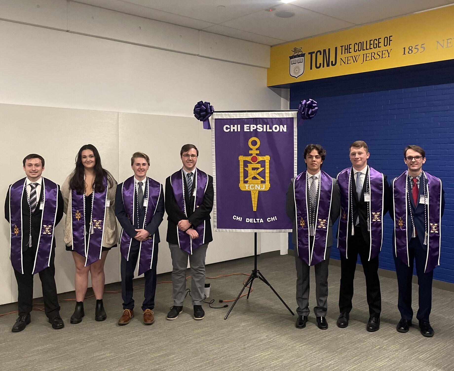 A group of students stand on each side of the banner.