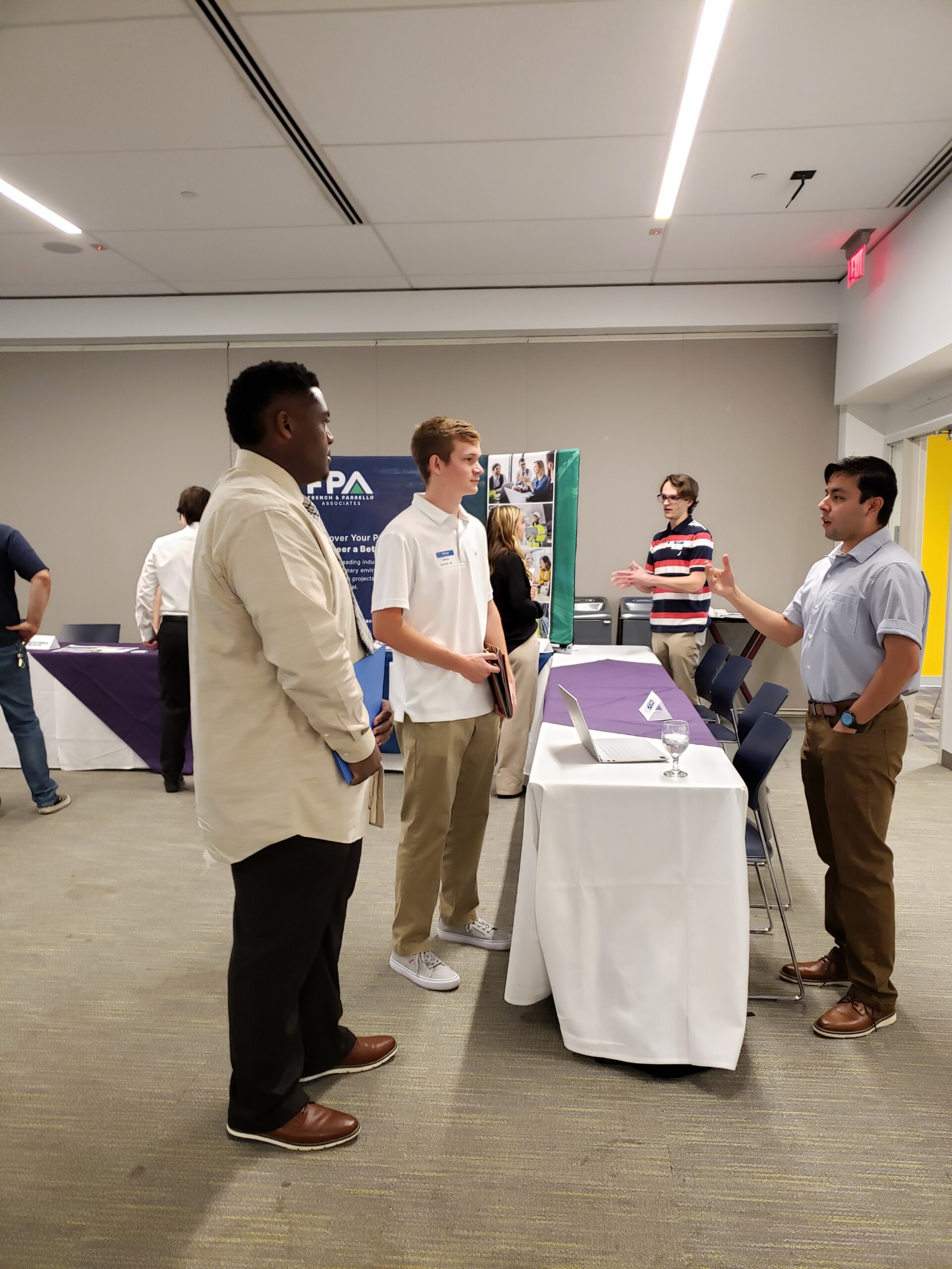 Students stand on one side of a table and alumni on the other during the networking event.