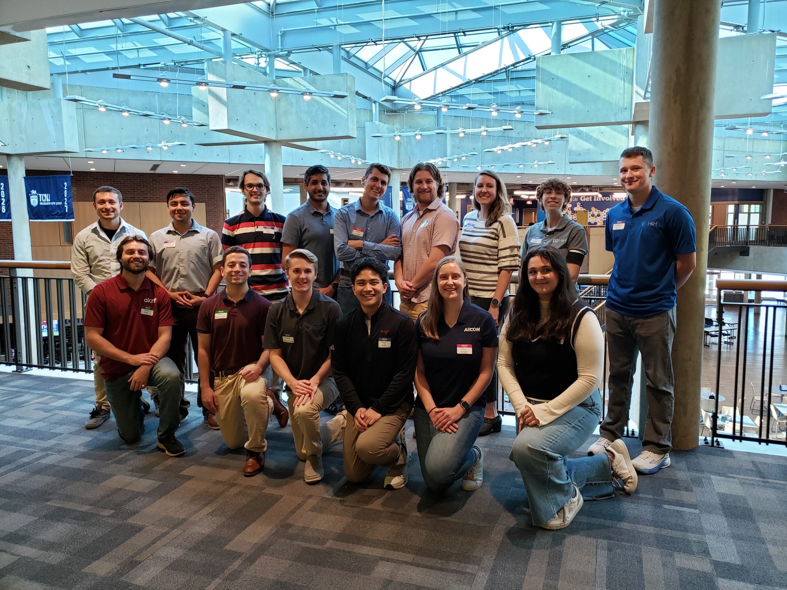 A group of 15 alumni, with half standing and half kneeling in front of them.