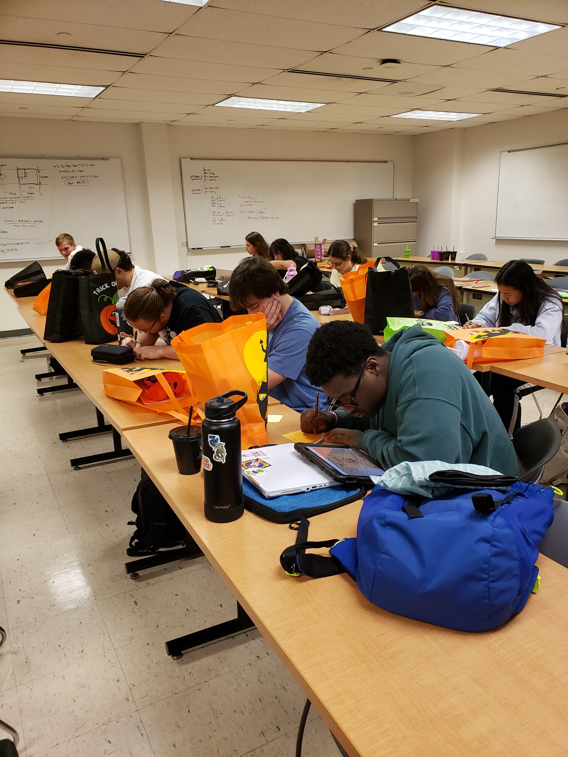 Students sitting at desks in a classroom drawing Halloween cards.