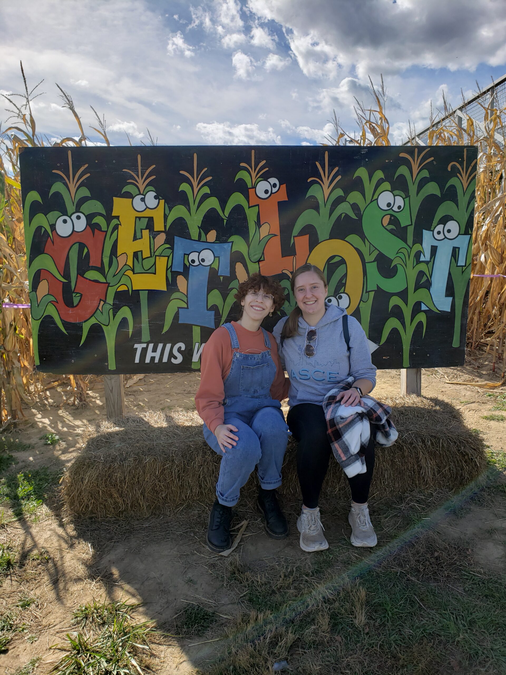 Two students sit in front of the sign that reads Get Lost
