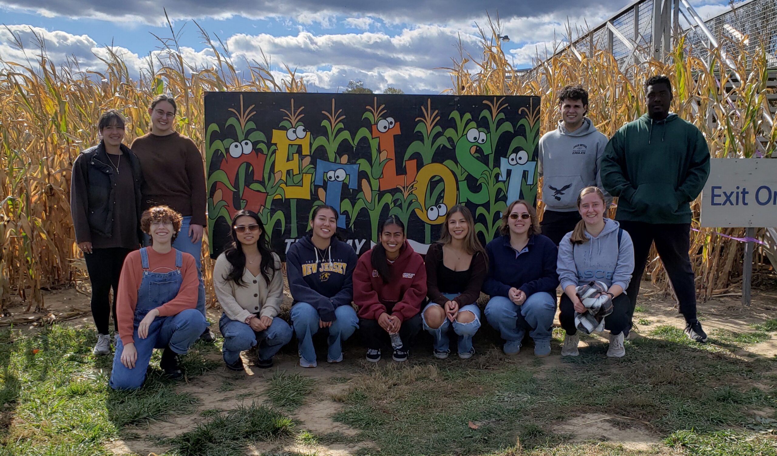 A group of students stand in front of a colorful sign that reads Get Lost.