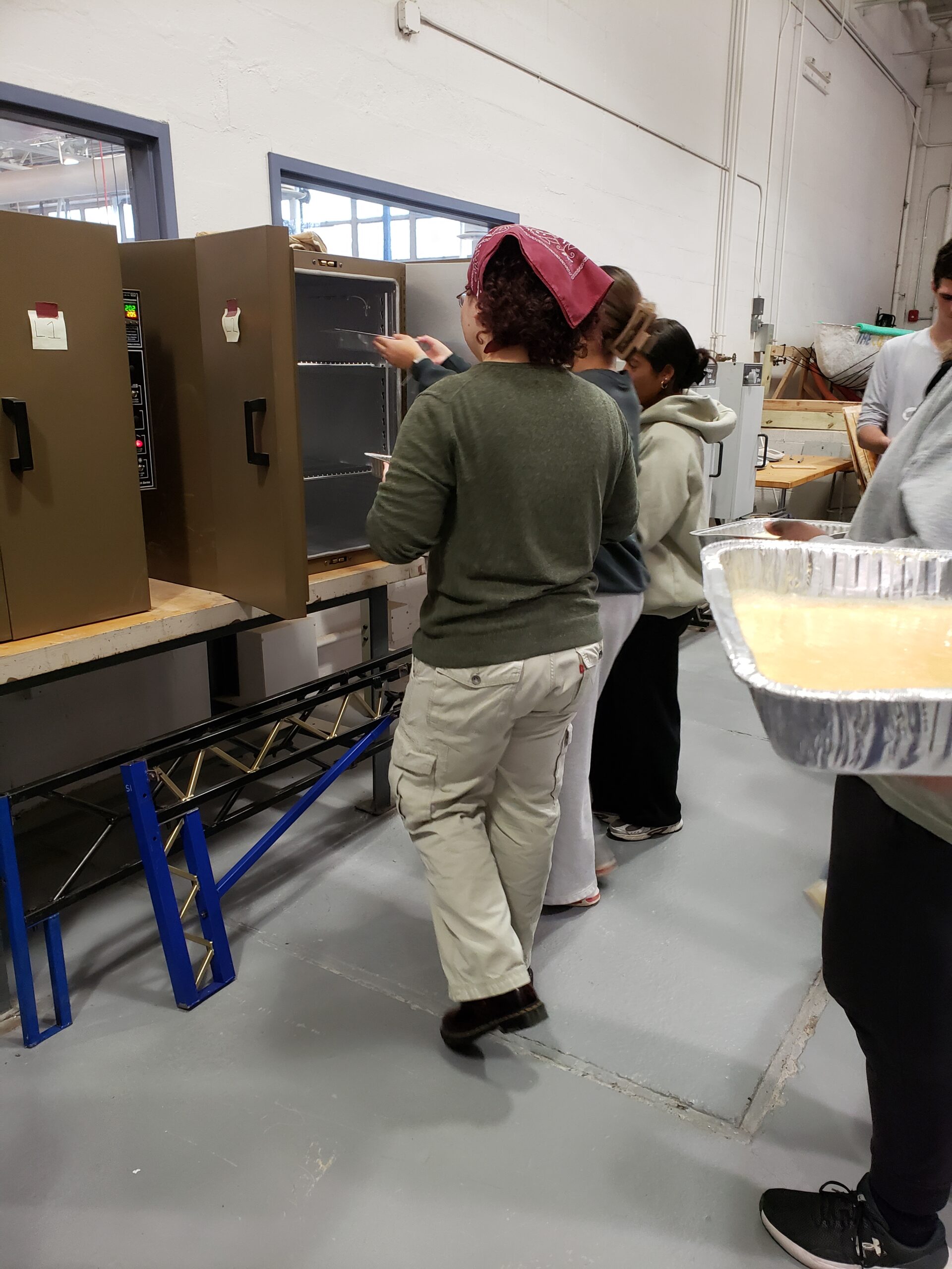 Students are placing pans in the oven.