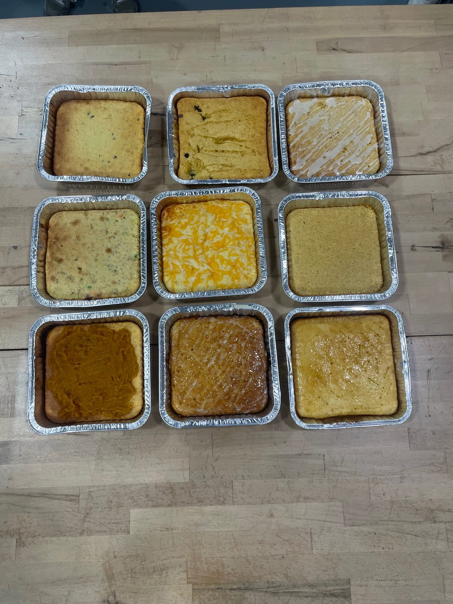 Nine pans with cornbread on the table.