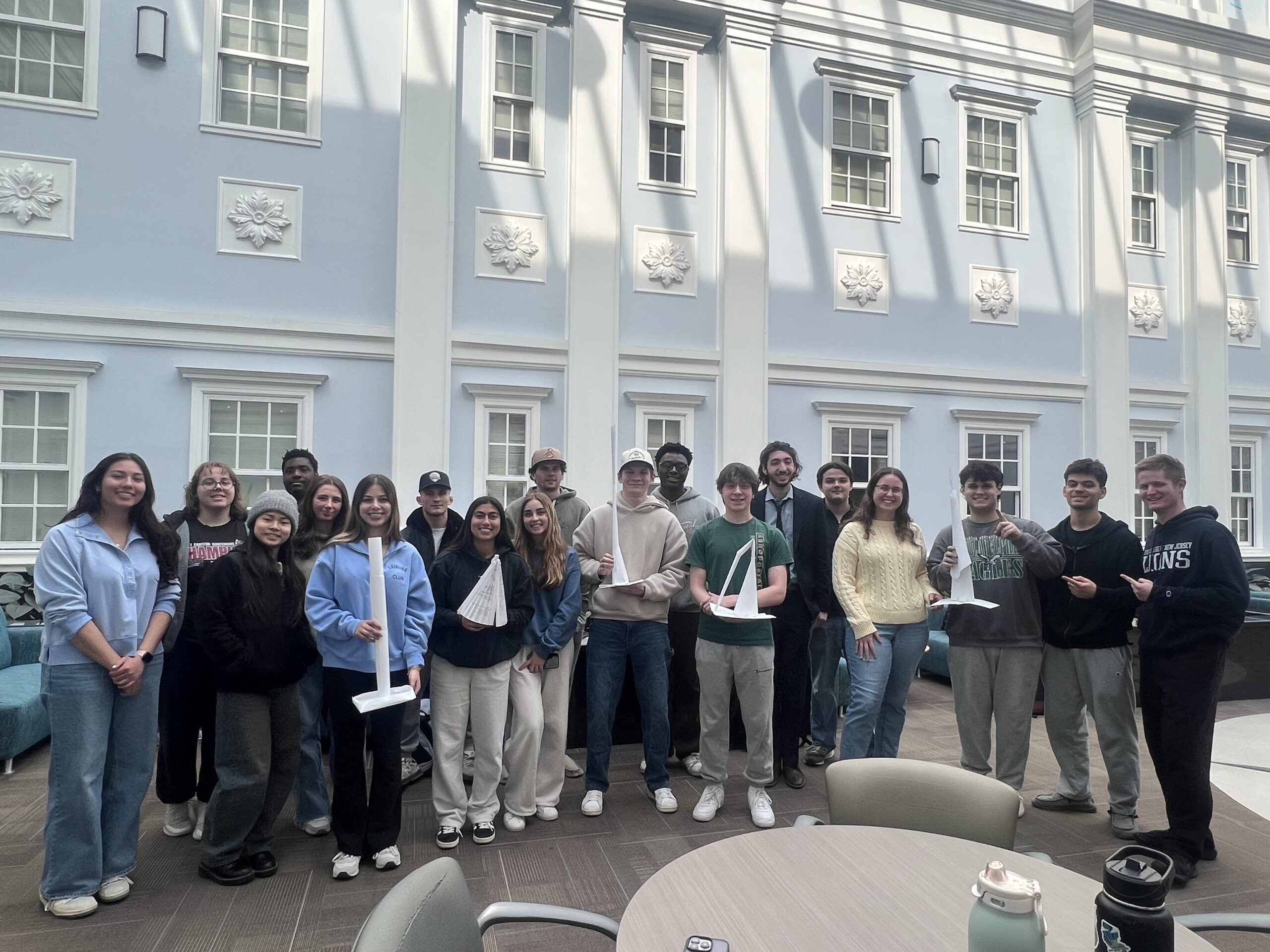 A group of students with students in the front row holding paper towers.