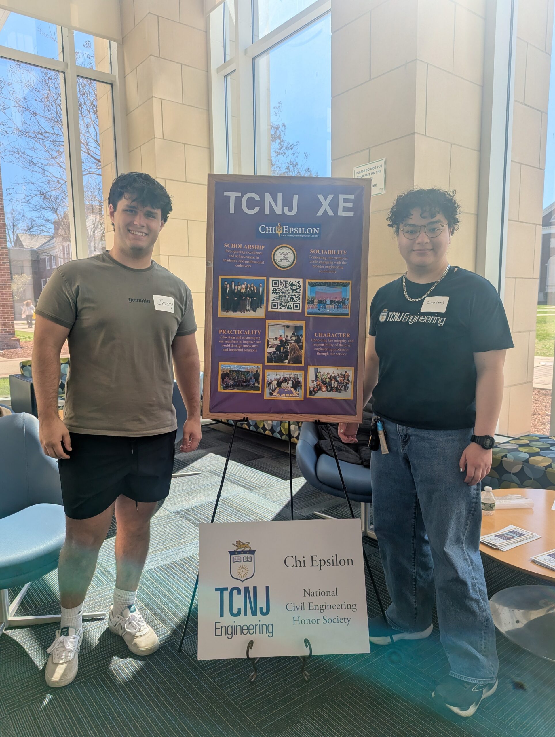 Two students standing on each side of a display board