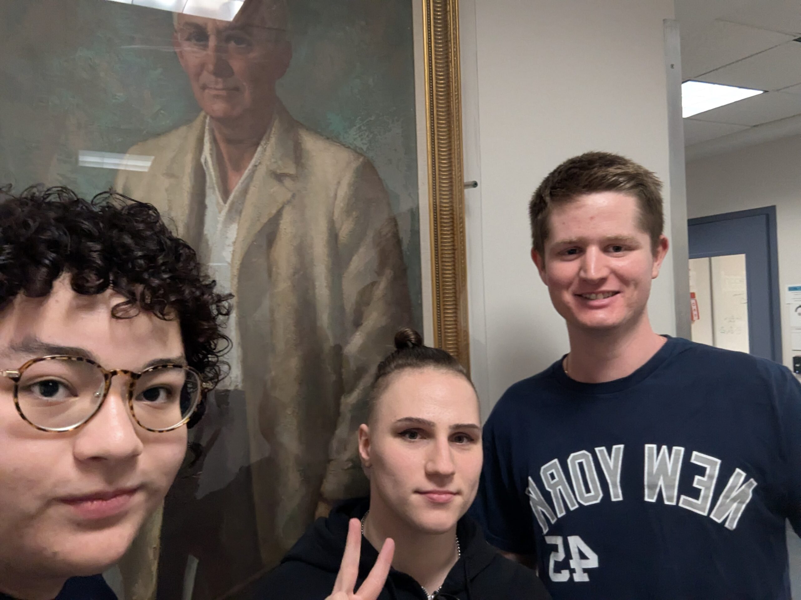Three students stand in front of a painting.