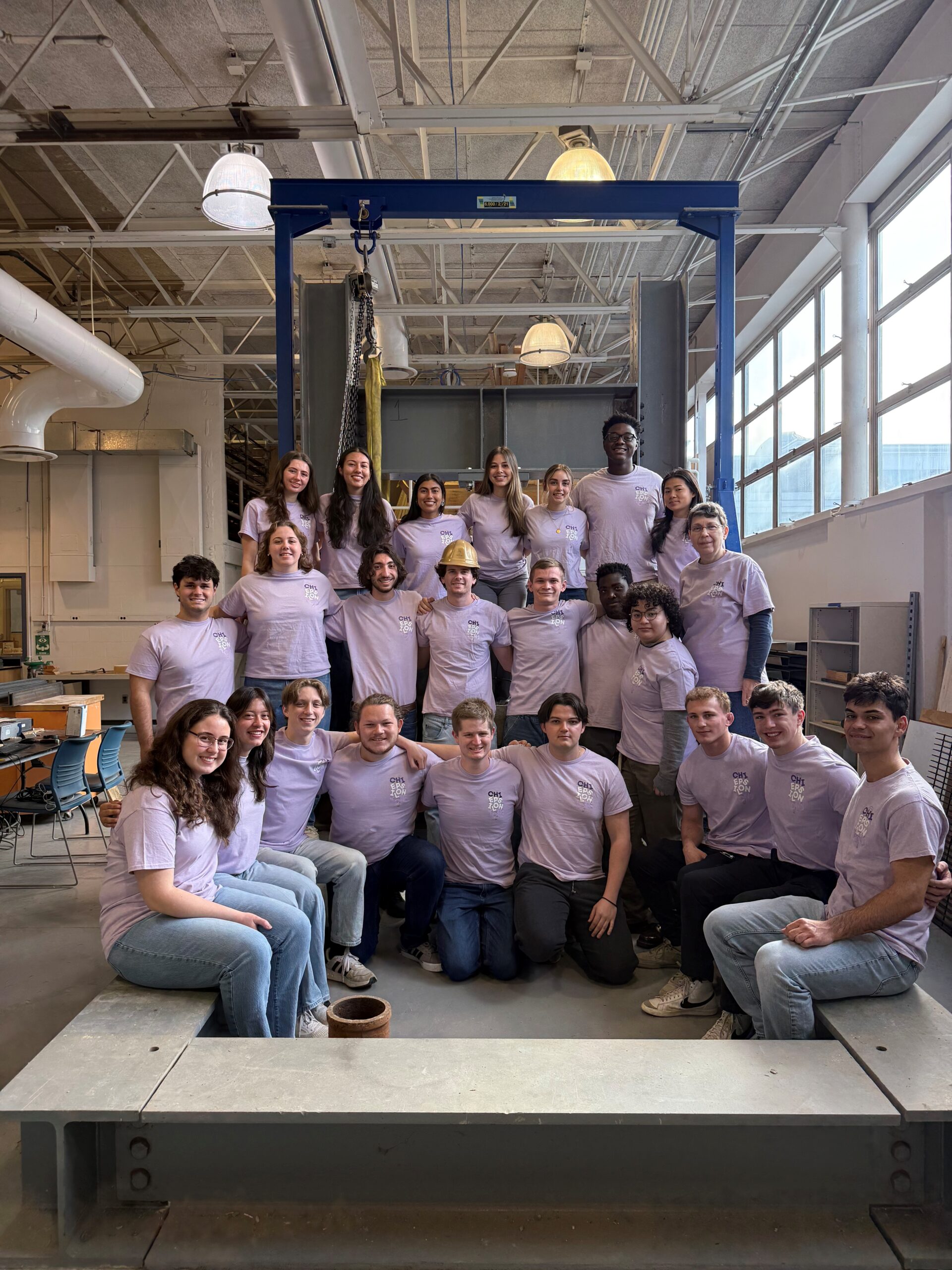 A large group of students in pink shirts standing around a load frame