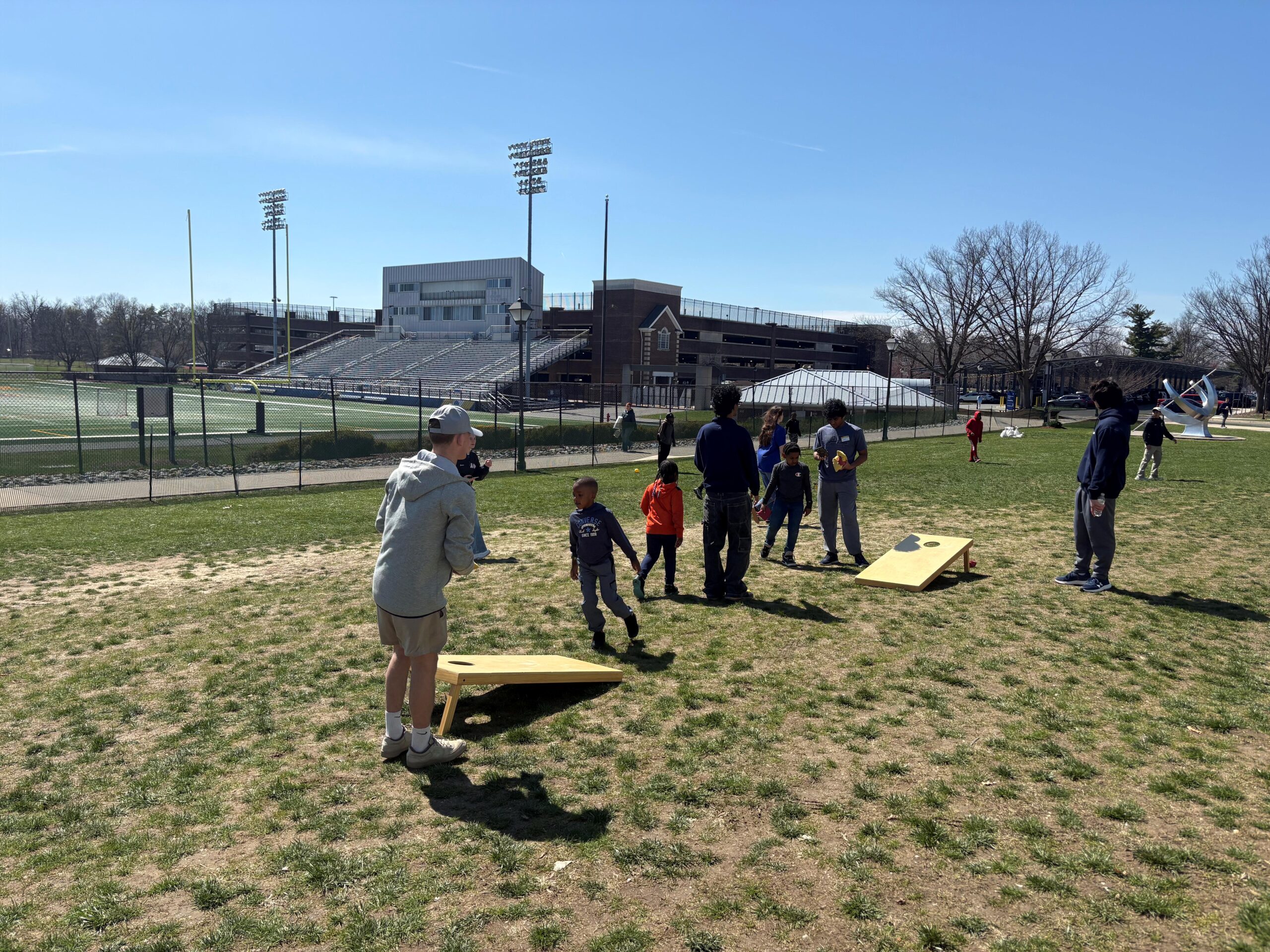 TCNJ students engaging with children in a game of cornhole