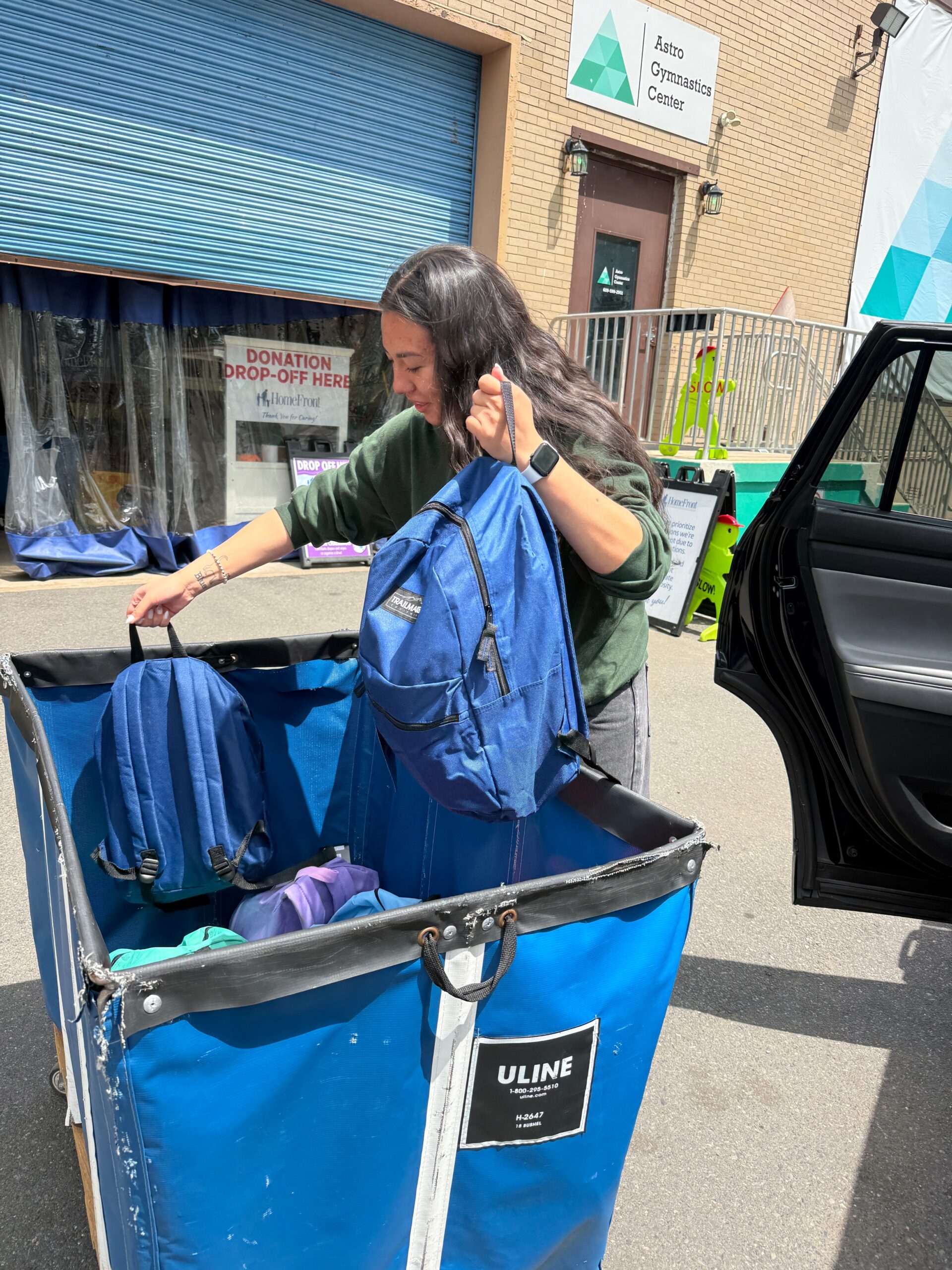 A female student is placing backpacks in a large collection bin