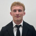 A headshot of a male in a dark suit and a dark tie