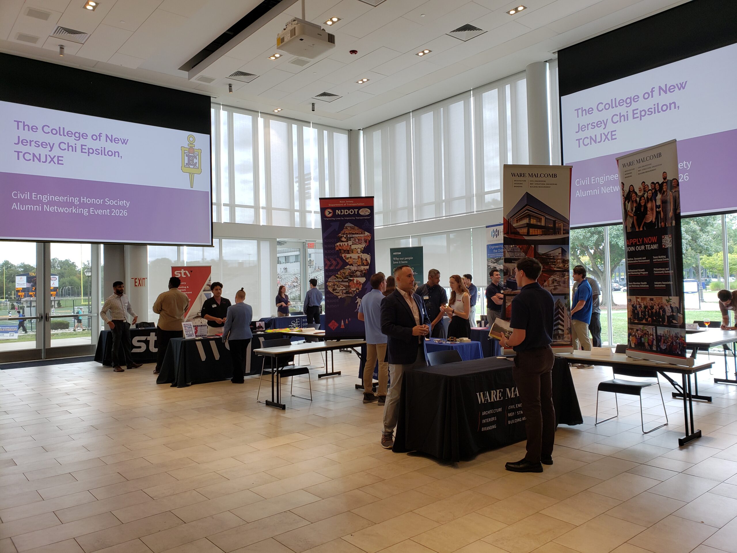 Students talking to alumni at varous stations. Many alumni displayed company posters.