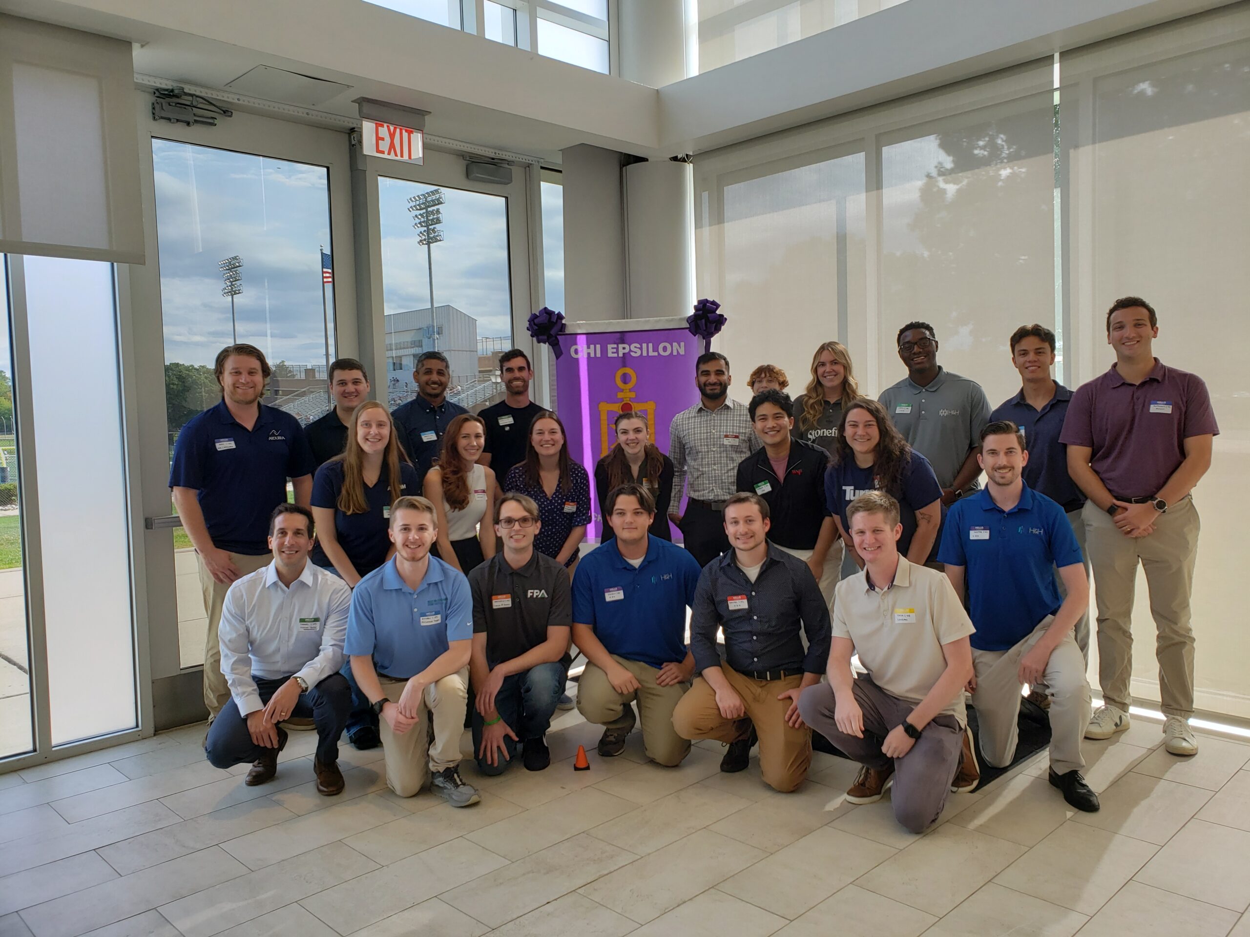 A group of young adults standing in three rows with the XE banner in the middle.