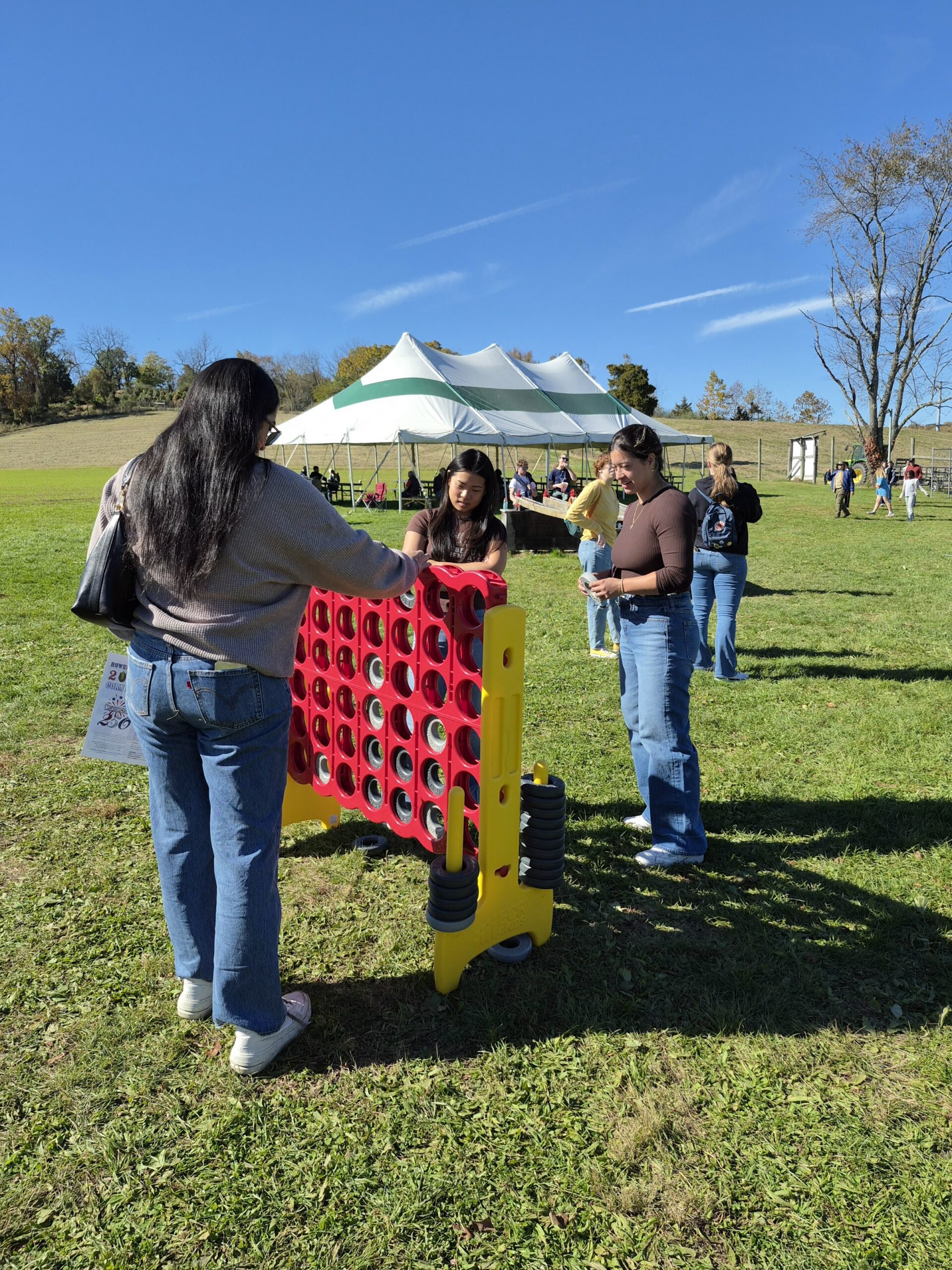Three female students are playing a large version of a tic tac toe game.